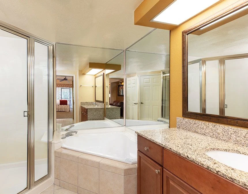 Bathroom of a Westgate Town Center Resort studio with a corner tub, glass shower and granite vanity
