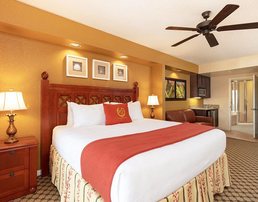 Westgate Town Center Resort studio with a bed in red and white bedding, a carved headboard and a ceiling fan