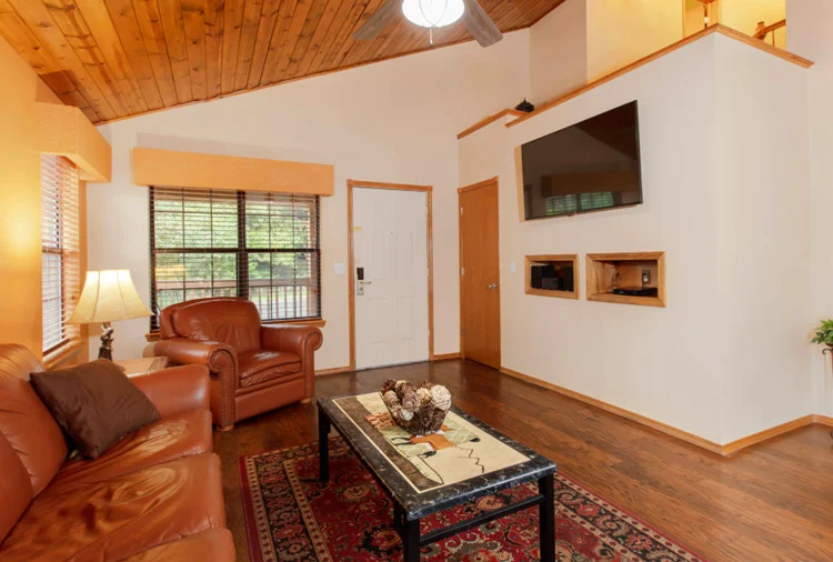 Living room of a Westgate Branson Woods two-bedroom villa with leather seating, a wood-plank ceiling and a wall-mounted TV