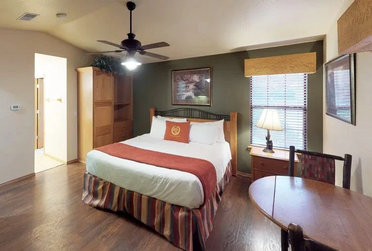 Westgate Branson Woods studio with a bed, wood armoire, round table and ceiling fan
