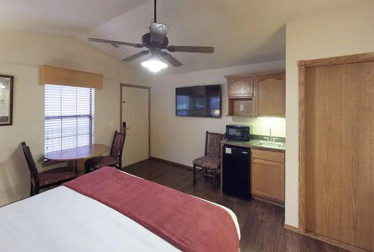 Westgate Branson Woods studio with a bed facing a kitchenette, wall-mounted TV and small dining table