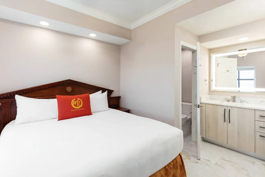 Bedroom of a Westgate Palace Resort two-bedroom villa with a bed, red accent pillow and open door to the bathroom