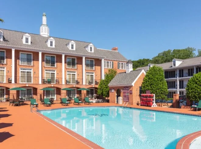 Outdoor pool beside red brick colonial-style buildings with a white cupola in Williamsburg, VA