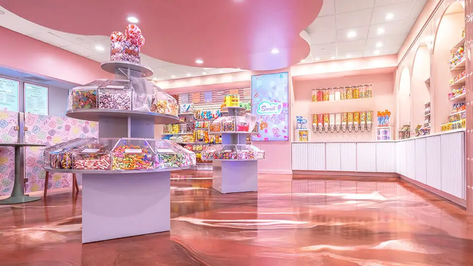 Pink candy shop with tiered candy displays in the center and shelves of sweets along the walls