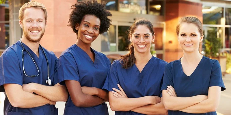 Four nurses in scrubs standing together with arms crossed
