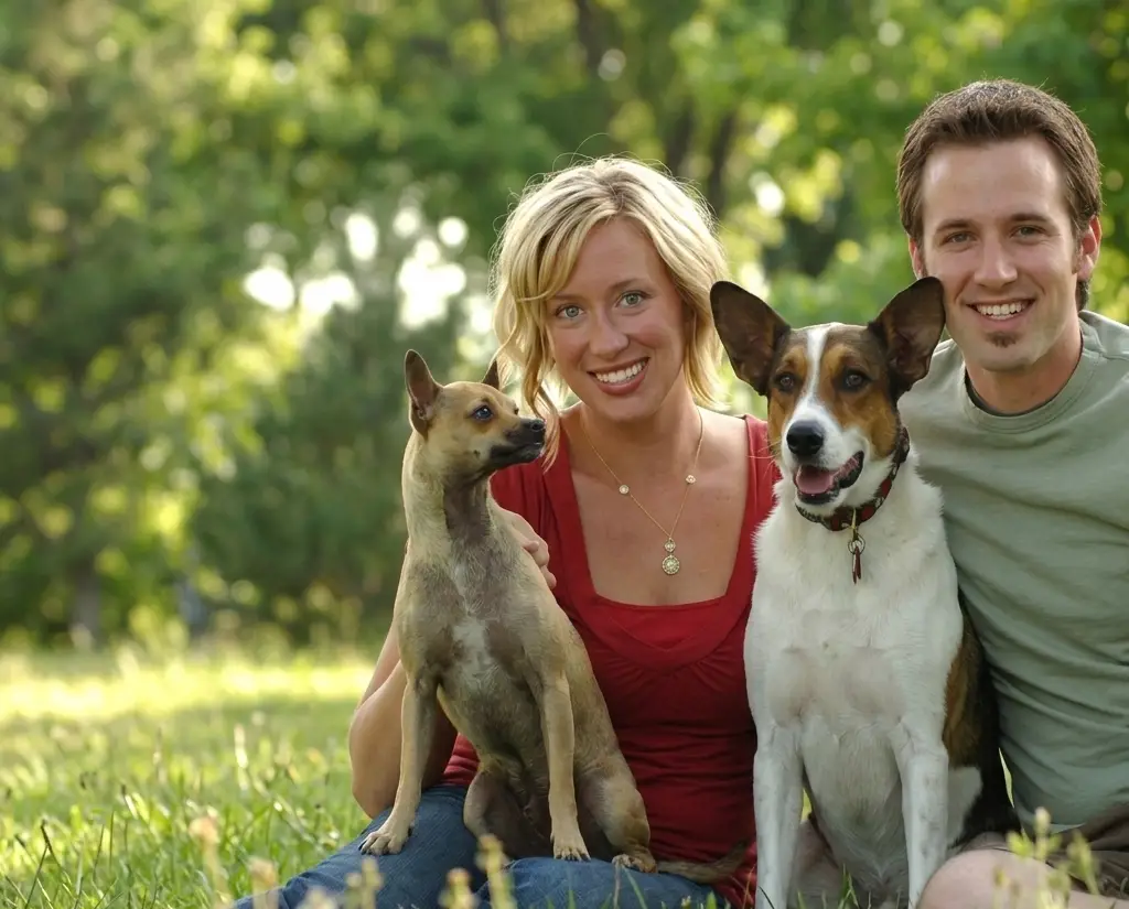 Couple sitting on the grass with their two dogs during a pet-friendly Westgate Resorts vacation