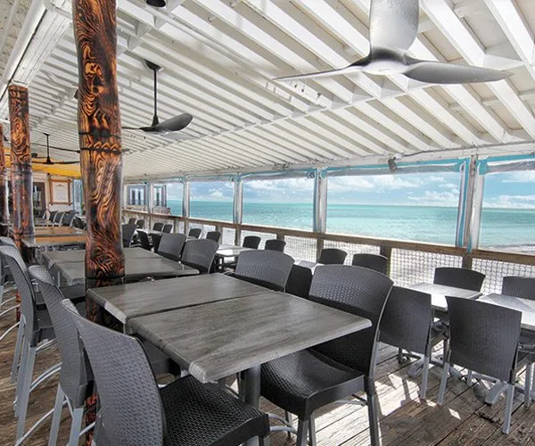 Covered deck with tables looking out over the ocean at The Boardwalk Bar