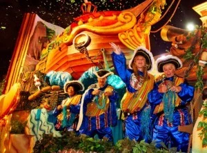 Costumed riders in blue and gold waving from a Mardi Gras parade float at Universal Orlando