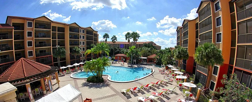Resort courtyard pool with umbrellas framed by balconied villa buildings
